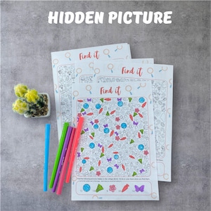 Può includere: Tre fogli di attività "Find it" con illustrazioni colorate e il testo "HIDDEN PICTURE". I fogli sono accompagnati da penne blu, verdi, rosa e viola. Un piccolo cactus in vaso si trova nell'angolo in alto a sinistra.