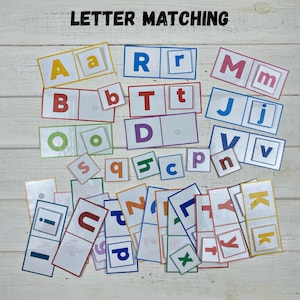 May include: A collection of colorful letter matching cards. The cards feature uppercase and lowercase letters in various colors, including yellow, red, blue, and green. The text "LETTER MATCHING" is at the top. This educational game is designed for early learning.