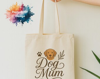 May include: A beige canvas tote bag with a brown dog graphic, paw print, and the words "Dog Mum" in elegant script. The bag is held up by a hand. The words "Printed DTF Design" are in the upper left corner.