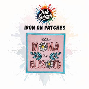 May include: Pink square iron-on patch with the text "this MAMA is BLESSED". The patch has a light blue border and features daisy and leaf designs. The Ink Splash logo is at the top. The patch is a decorative item.