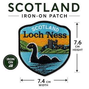 May include: An iron-on patch featuring a black Loch Ness monster in blue water, a green landscape, and a castle silhouette against a yellow sky. The text reads SCOTLAND, IRON-ON PATCH, and Loch Ness. It measures 7.6 cm in height and 7.4 cm in width.
