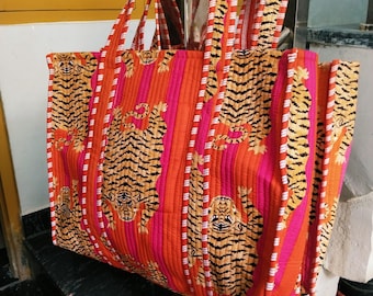 Könnte beinhalten: Große Tragetasche mit einem lebendigen Tigerdruck. Die Tasche hat ein gestepptes Design mit orangefarbenen, rosa und weißen Streifen. Das Tigermuster ist in Schwarz und Gelb. Die Tasche hat zwei lange Griffe.
