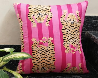 May include: A square decorative pillow with a pink and magenta striped background. The pillow features multiple tiger illustrations in shades of tan and black. The tigers are in various poses, adding a playful touch to the design.