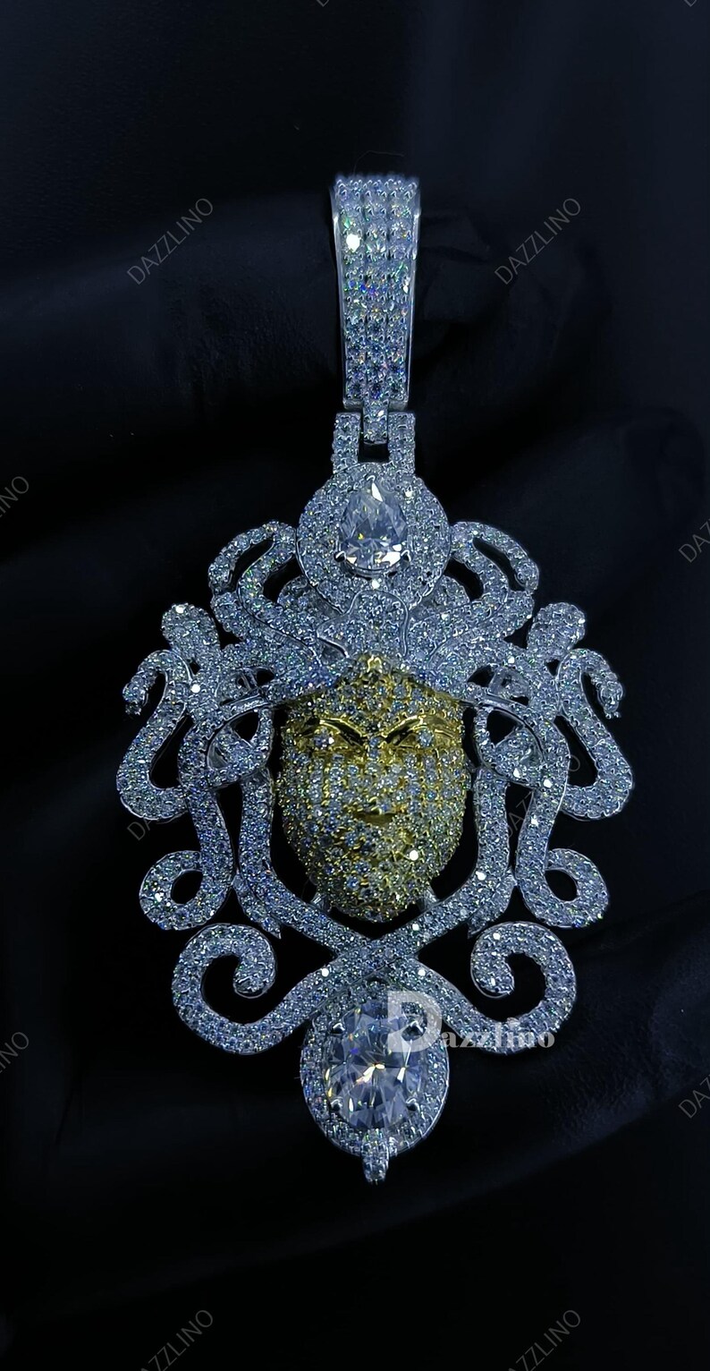 May include: A dazzling pendant featuring a gold-toned face with intricate detailing, surrounded by a silver-colored, ornate design. The pendant is encrusted with numerous sparkling stones, creating a luxurious and eye-catching piece of jewelry.