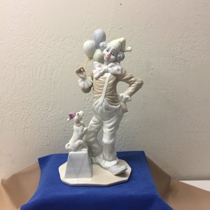 Vintage porcelain figurine of a clown holding balloons, with a dog sitting on a box