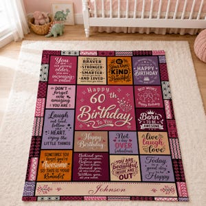 May include: A rectangular throw blanket featuring a patchwork design with various inspirational quotes and birthday messages in shades of pink, purple, and orange. The center text reads Happy 60th Birthday To You, with the name Johnson at the bottom.