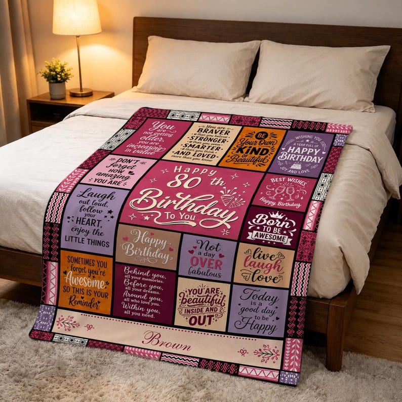 May include: A rectangular throw blanket featuring a patchwork design with various inspirational quotes and the text "Happy 80th Birthday To You" and "Brown" in the center. The blanket uses a color palette of pink, purple, orange, and cream.