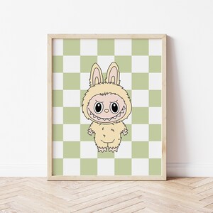May include: A framed print featuring a cartoon character in a bunny costume. The character has a menacing grin and is set against a green and white checkered background. The artwork is in a wooden frame and is displayed on a white wall.