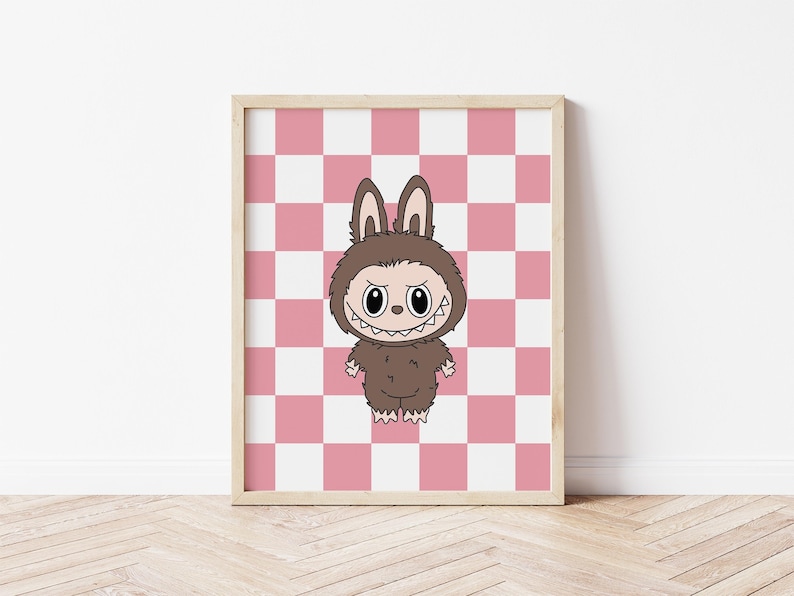 May include: A framed print featuring a cartoon character in a brown bunny costume with a menacing grin. The character stands against a pink and white checkered background. The frame is a light wood color.