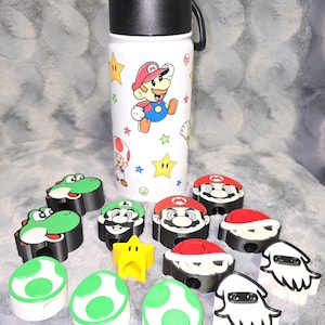May include: White water bottle with a black lid and handle, featuring a colorful Mario Bros. design. Assorted character pencil toppers and erasers, including Yoshi, Mario, Luigi, and star shapes. A fun, themed collection.