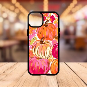 May include: A black phone case with a floral design featuring pink, orange, and white pumpkins. The case has a cutout for the camera lens.