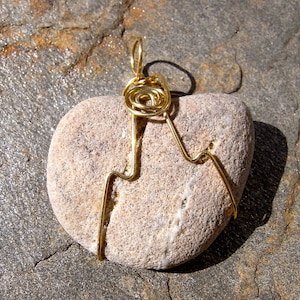 Op de afbeelding: Een hartvormige stenen hanger met een ontwerp van gouden draad. De draad is om de steen gewikkeld en vormt bovenaan een werveling, waardoor er een lus ontstaat om hem op te hangen.