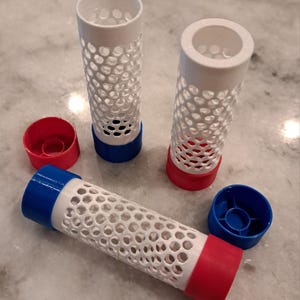 May include: A collection of 3D-printed cylindrical objects with a white, perforated design. The objects have red and blue accents on the ends. Two cylindrical objects are upright, and one is horizontal. Two red and two blue caps are also present.