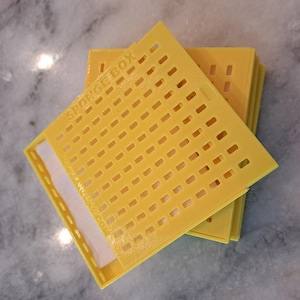 May include: A stack of bright yellow sponge boxes with a perforated design. The text "SPONGE BOX" is visible on the top box. The boxes are rectangular with a white mesh material visible inside.