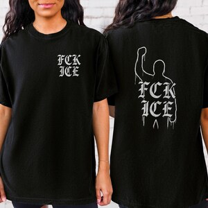 Puede incluir: Camiseta negra con el texto "FCK ICE" en fuente g&oacute;tica en la parte delantera y una silueta de pu&ntilde;o en alto con el mismo texto en la parte trasera. La camiseta es de cuello redondo y manga corta.