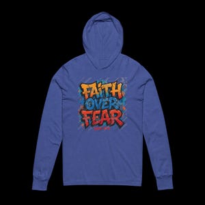 Peut inclure: Un sweat &agrave; capuche bleu avec des manches longues. Le devant pr&eacute;sente les mots "FAITH OVER FEAR" dans un design de style graffiti avec des couleurs orange, bleu et rouge. Le sweat &agrave; capuche a une capuche &agrave; cordon.