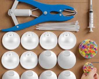 May include: A collection of tools and supplies, including a blue and white applicator, white plastic spheres, a syringe, zip ties, and a stress ball filled with colorful beads. The items are arranged on a brown cardboard surface.
