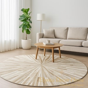May include: A round, beige and cream-colored rug with a sunburst design. The rug is made of rectangular pieces of varying shades of beige and cream. The rug is in a living room setting with a sofa, coffee table, and a potted plant.