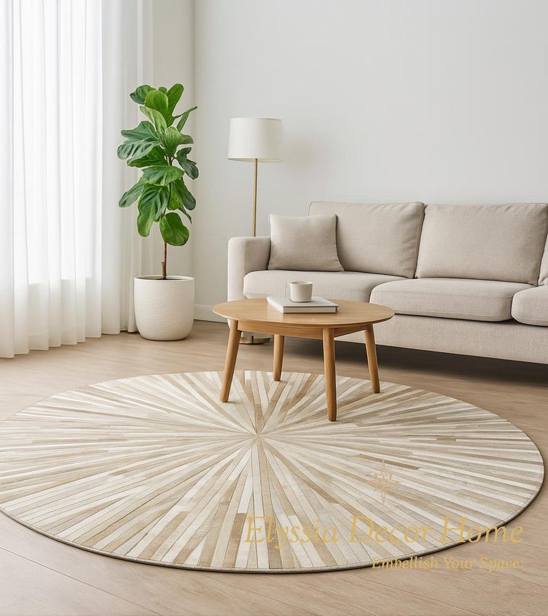May include: A round, beige and cream-colored rug with a sunburst design. The rug is made of rectangular pieces of varying shades of beige and cream. The rug is in a living room setting with a sofa, coffee table, and a potted plant.