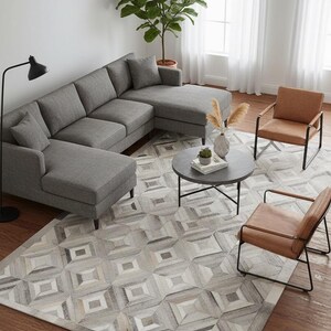 Könnte beinhalten: Draufsicht auf ein modernes Wohnzimmer mit einem grauen Ecksofa, zwei braunen Ledersesseln und einem geometrisch gemusterten Teppich. Ein runder Couchtisch und eine Stehlampe sind ebenfalls zu sehen. Der Raum ist hell beleuchtet.