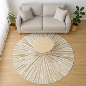 May include: A round rug with a sunburst pattern in shades of beige and cream sits beneath a small, round wooden coffee table. A beige sofa with two matching pillows is positioned behind the table. Potted plants flank the sofa, adding a touch of greenery.
