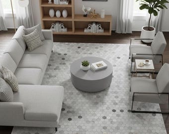 May include: A contemporary living room featuring a light grey sectional sofa, two armchairs, and a circular coffee table. A hexagonal patterned rug covers the floor. A wooden bookshelf and artwork are in the background. The text "Elyssia Decor Home" is on the rug.