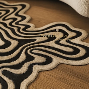 May include: A decorative rug with a unique, flowing design. The rug features a cream-colored, textured background with bold black, wavy stripes. The rug's edge is also cream-colored, and the text "Elyssia Decor Home" is visible.