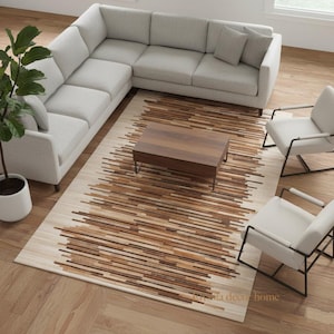 May include: A modern living room setup featuring a light gray sectional sofa, two armchairs, and a rectangular wooden coffee table. A patterned rug with brown and beige stripes adds warmth. A potted plant sits nearby.