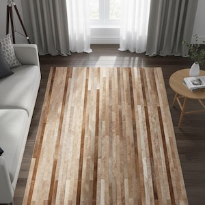 Peut inclure: Tapis rectangulaire avec un motif de grain de bois naturel. Le tapis présente des rayures verticales dans différentes nuances de marron et de beige, créant un aspect texturé. Il est posé sur un sol en bois foncé.