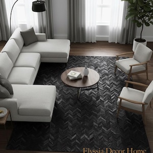 May include: An interior shot of a modern living room with a white sectional sofa, two armchairs, and a round coffee table. A black chevron patterned rug covers the floor. A floor lamp and a potted plant are also visible. The room is well-lit with natural light.
