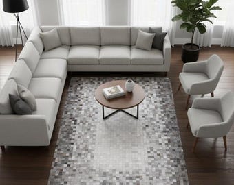 May include: A large light grey sectional sofa with matching throw pillows, two light grey armchairs, and a round wooden coffee table. A rectangular area rug features a pixelated grey and white pattern. Text in the corner reads Elyssa Decor Home.