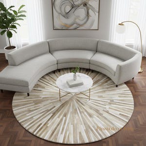 Może przedstawiać: Jasnoszara, zakrzywiona sofa modułowa z pasującym okrągłym stolikiem kawowym i wzorzystym dywanem. Dywan ma wzór promieni słonecznych w odcieniach beżu i bieli. Widoczna jest również lampa podłogowa z białym kloszem w kształcie kuli i roślina doniczkowa.