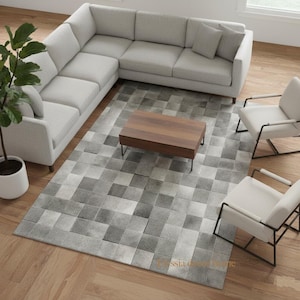 Peut inclure: Aménagement de salon moderne avec un canapé d'angle gris clair, deux fauteuils blancs avec des cadres en métal noir et une table basse rectangulaire en bois. Un tapis à carreaux gris et blanc recouvre le sol. Une plante en pot ajoute de la verdure.