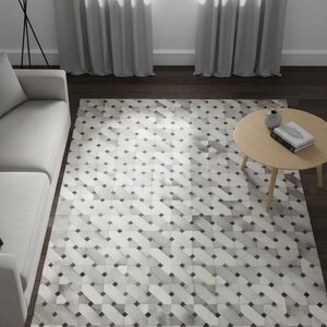 Pode incluir: Um tapete com padrão geométrico em tons de cinza e branco domina a sala. O tapete apresenta um padrão repetitivo de retângulos angulados e quadrados cinza escuro. O texto "Elyssia Decor Home" é visível. Um sofá claro e uma mesa redonda também estão presentes.