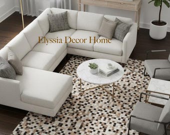 May include: A contemporary living room arrangement with a white corner sofa, a patterned rug, and a marble-topped coffee table. The room is decorated in neutral colours and includes a console table, artwork, and a potted plant.