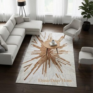 Op de afbeelding: Een moderne woonkamer met een lichtgrijze hoekbank, twee fauteuils en een ronde houten salontafel. Een groot vloerkleed met een sunburst-ontwerp in wit- en bruintinten is het middelpunt. De tekst "Elyssia Decor Home" staat op het vloerkleed.