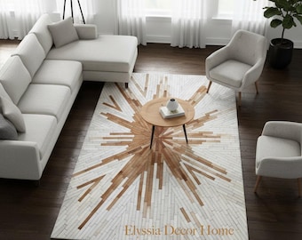 May include: A modern living room featuring a light gray sectional sofa, two armchairs, and a round wooden coffee table. A large area rug with a sunburst design in white and brown tones is the focal point. The text "Elyssia Decor Home" is on the rug.