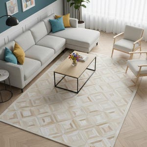 May include: A contemporary living room featuring a light grey sectional sofa, two armchairs, and a wooden coffee table. A large rug with a geometric pattern is on the floor. The room is decorated with artwork and plants. The text "Elyssia decor home" is visible.