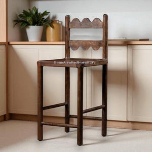 K&ouml;nnte beinhalten: Ein hoher, dunkelbrauner Barhocker aus Holz mit einer wellenf&ouml;rmigen R&uuml;ckenlehne. Der Hocker hat eine rechteckige Sitzfl&auml;che und vier gerade Beine mit einer Fu&szlig;st&uuml;tze. Der Text "HomeCraftedFurniture" ist auf dem Sitz zu sehen.