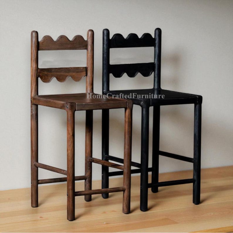 K&ouml;nnte beinhalten: Zwei Barhocker aus Holz. Einer ist mittelbraun gebeizt, der andere ist schwarz lackiert. Beide haben eine wellenf&ouml;rmige obere Schiene und einen quadratischen Sitz. Der Text "HomeCraftedFurniture" ist auf dem schwarzen Hocker sichtbar.