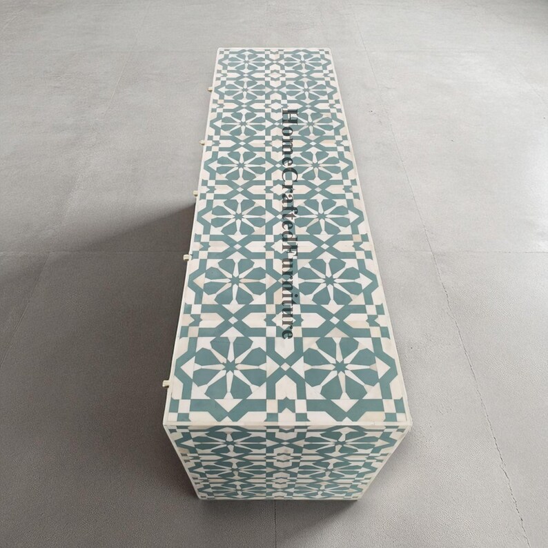 Puede incluir: Mesa de centro rectangular con un patr&oacute;n geom&eacute;trico en color turquesa y blanco. La superficie presenta un dise&ntilde;o repetitivo de estrellas y cruces. El texto "Home Crafted Furniture" est&aacute; impreso verticalmente en el lateral de la mesa.