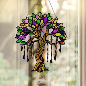 Op de afbeelding: Gebrandschilderde boom zonnevanger met een gedetailleerd ontwerp. De boom heeft een bruine stam en takken, met kleurrijke bladeren in groen, geel en paars. Decoratieve kralenkettingen hangen aan de takken en voegen een vleugje elegantie toe.