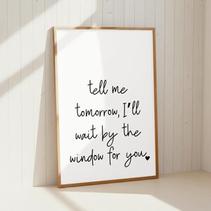 Könnte beinhalten: Ein gerahmter Druck mit weißem Hintergrund und Holzrahmen. Der handschriftliche Text in Schwarz lautet: "tell me tomorrow, I'll wait by the window for you." Am Ende des Textes befindet sich ein kleines schwarzes Herz.