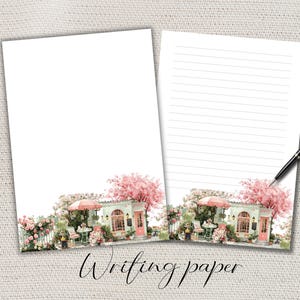 May include: Two sheets of white writing paper featuring a watercolour illustration of a cafe scene. The cafe has a pink door, a red umbrella, and pink flowering trees. The words "Writing paper" are written in cursive.