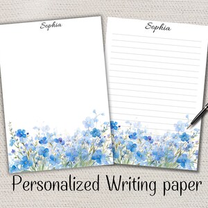Peut inclure: Deux feuilles de papier à écrire blanches avec un motif floral. Le bas de chaque feuille présente des fleurs bleues à l'aquarelle et du feuillage vert. Le mot "Sophia" est écrit en haut. Le texte "Personalized Writing paper" est en bas.