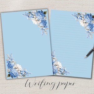 May include: Two sheets of light blue stationery, one blank and one with horizontal lines, both featuring floral arrangements of blue and white hydrangeas in the top right and bottom left corners, accompanied by a black ballpoint pen.