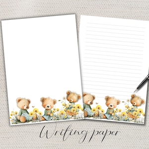 Puede incluir: Dos hojas de papel de escritura blanco con un borde decorativo con osos de peluche de acuarela en un campo de flores amarillas. Una hoja está rayada y un bolígrafo negro descansa sobre el papel. Las palabras "Writing paper" están escritas en cursiva.