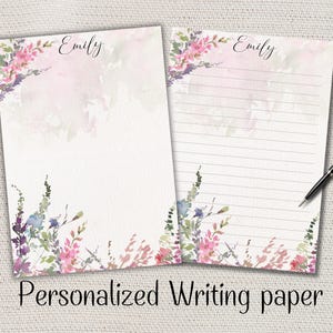 Peut inclure: Deux feuilles de papier à lettres personnalisées avec des motifs floraux à l'aquarelle. Le haut de chaque feuille est personnalisé avec le nom "Emily" en écriture cursive. Le bas et les coins supérieurs gauches du papier sont décorés de fleurs roses, violettes et bleues. Le bas de l'image indique "Personalized Writing paper".