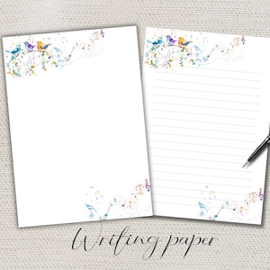 Puede incluir: Dos hojas de papel de escritura blanco con un diseño de acuarela de pájaros, notas musicales y elementos florales. Una hoja está rayada y la otra en blanco. Un bolígrafo negro descansa sobre la hoja rayada. Las palabras "Writing paper" están escritas en la parte inferior.