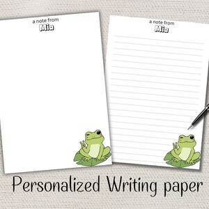 Peut inclure: Deux feuilles de papier à écrire personnalisées blanches avec une illustration de grenouille de dessin animé. Une feuille est vierge, l'autre a des lignes horizontales. Le texte "a note from Mia" est en haut de chaque feuille. Le texte "Personalized Writing paper" est en bas.